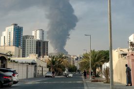 A cloud of smoke rises above city buildings.